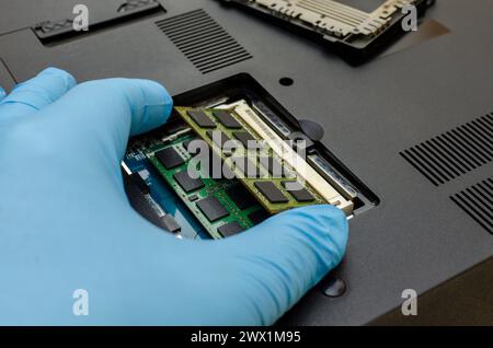 Computer service`s hand extracts internal memory from the inside of the laptop Stock Photo